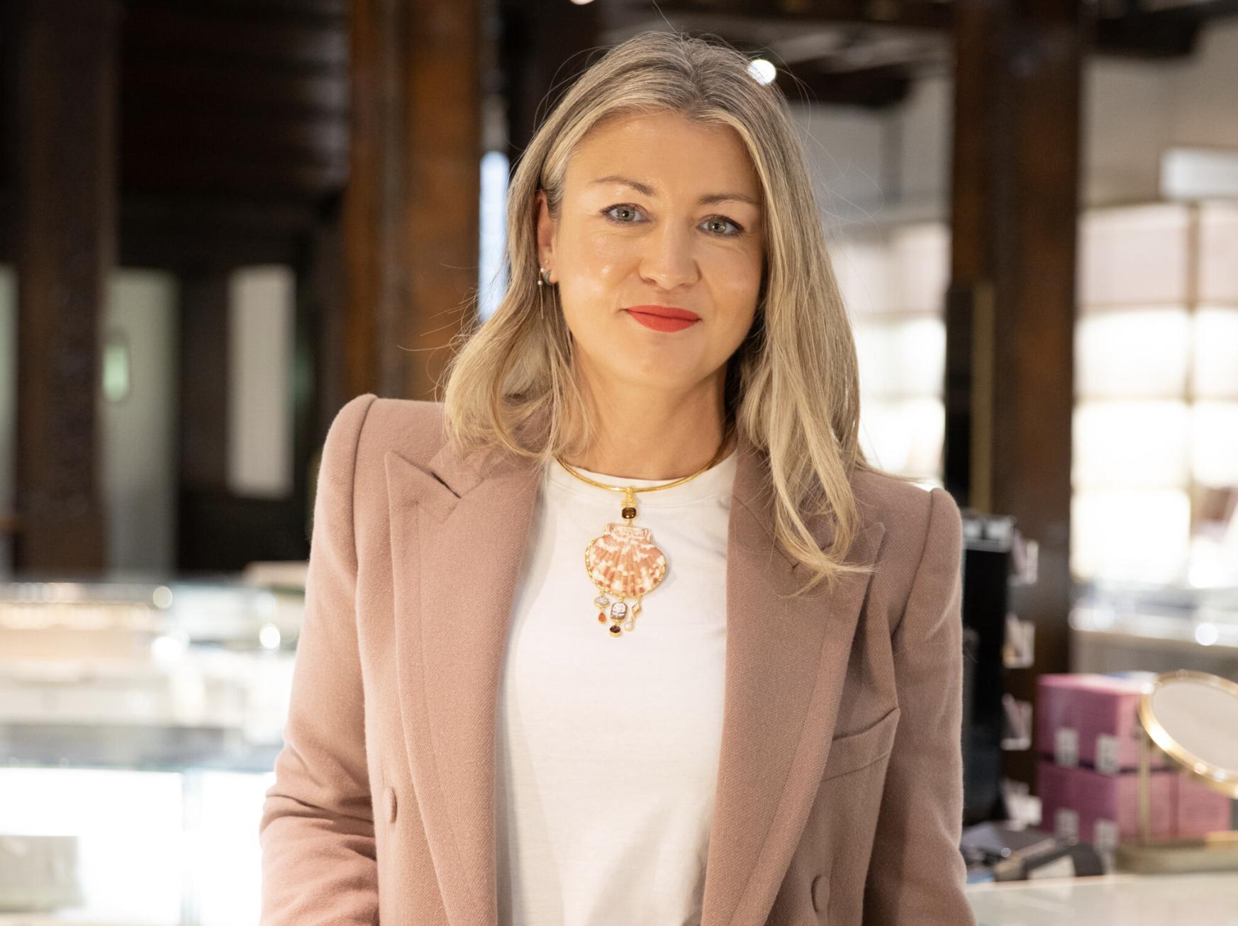 Ruby Beales, Liberty&rsquo;s Jewellery Buying Manager, wearing a shell pendant and pale pink blazer inside the jewellery gallery.