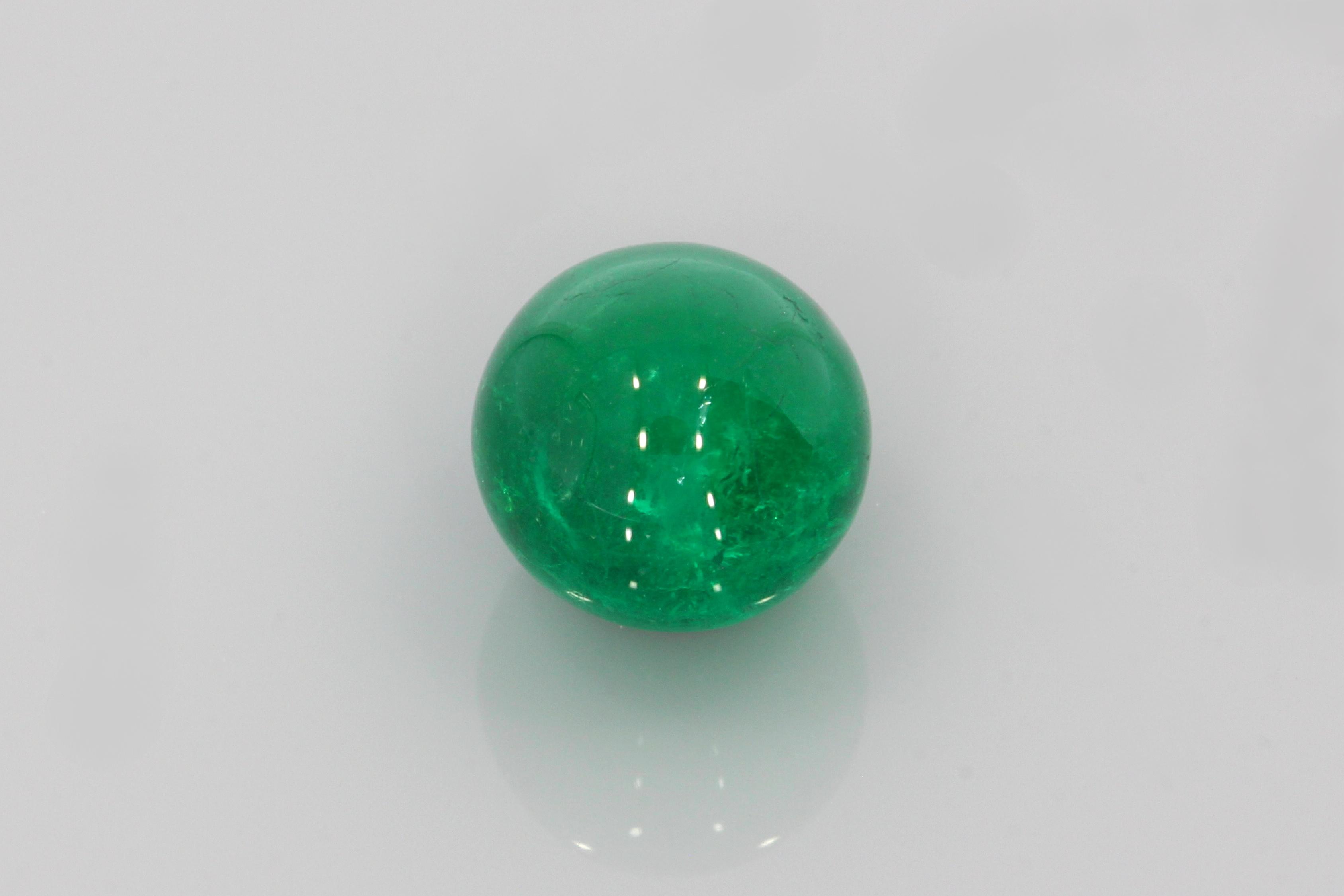 Polished round emerald sphere with vivid green colour displayed against a white background.