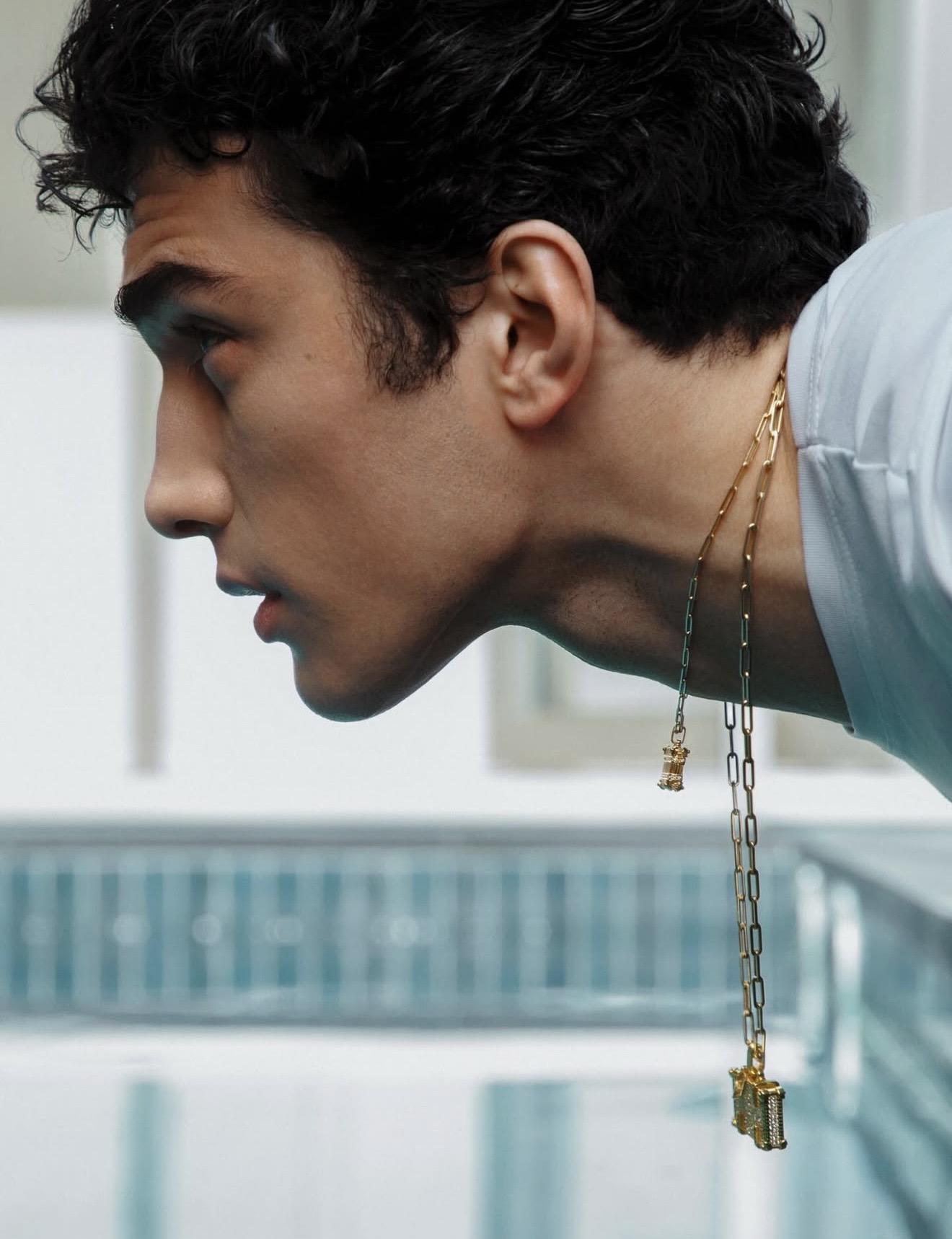 Side profile of a model wearing long gold chain necklaces with pendants hanging down the neck. NeverNot Jewellery