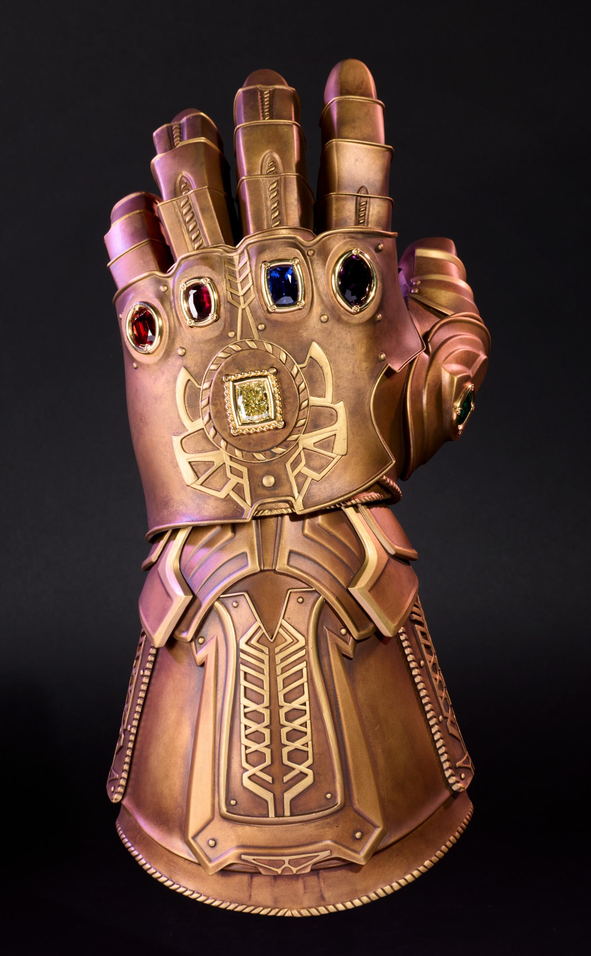 Front view of the bronze-coloured Marvel Infinity Gauntlet set with six red, blue, purple, yellow and green gemstones.