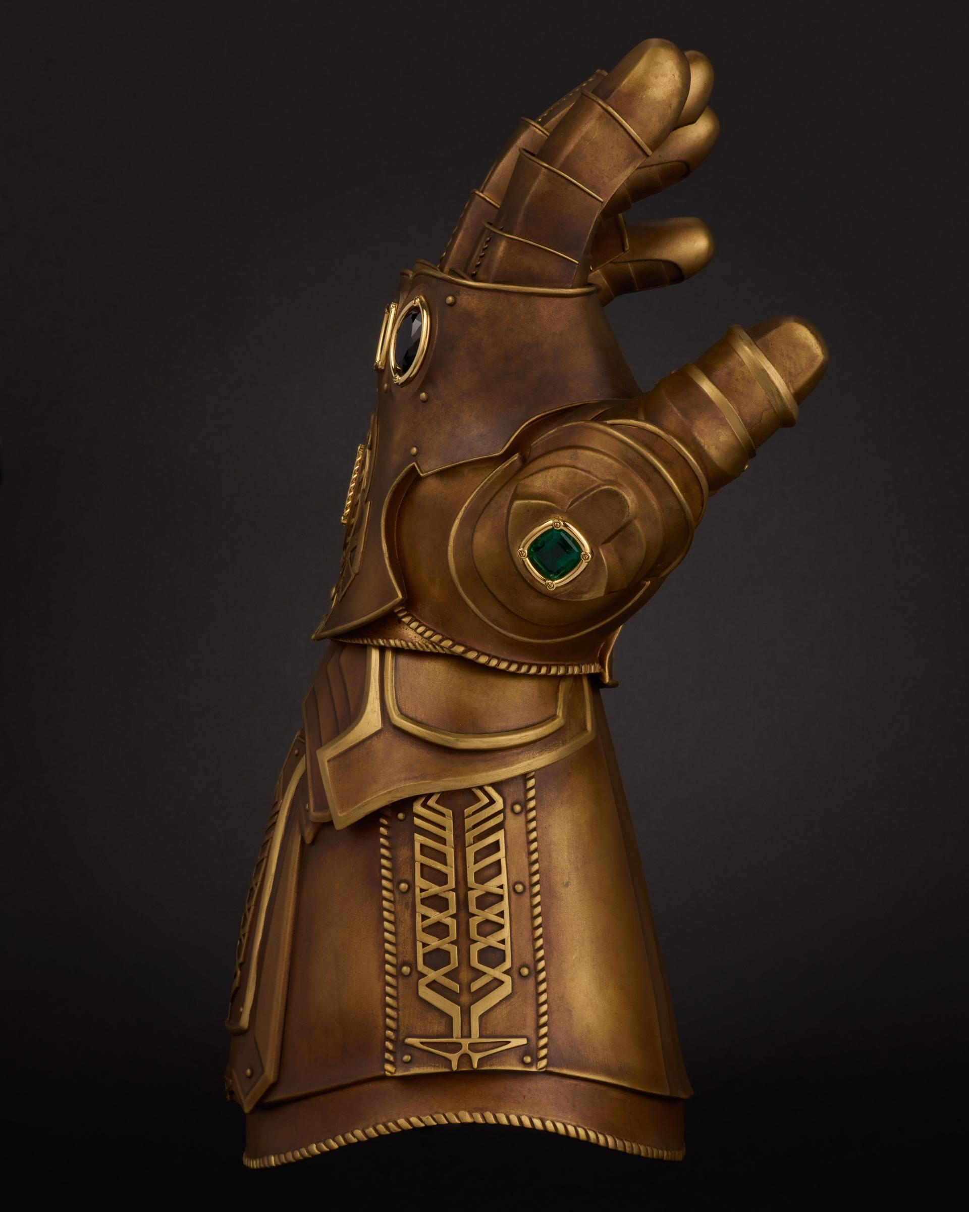 ide view of the bronze-coloured Marvel Infinity Gauntlet showing the green emerald Time Stone on the thumb.