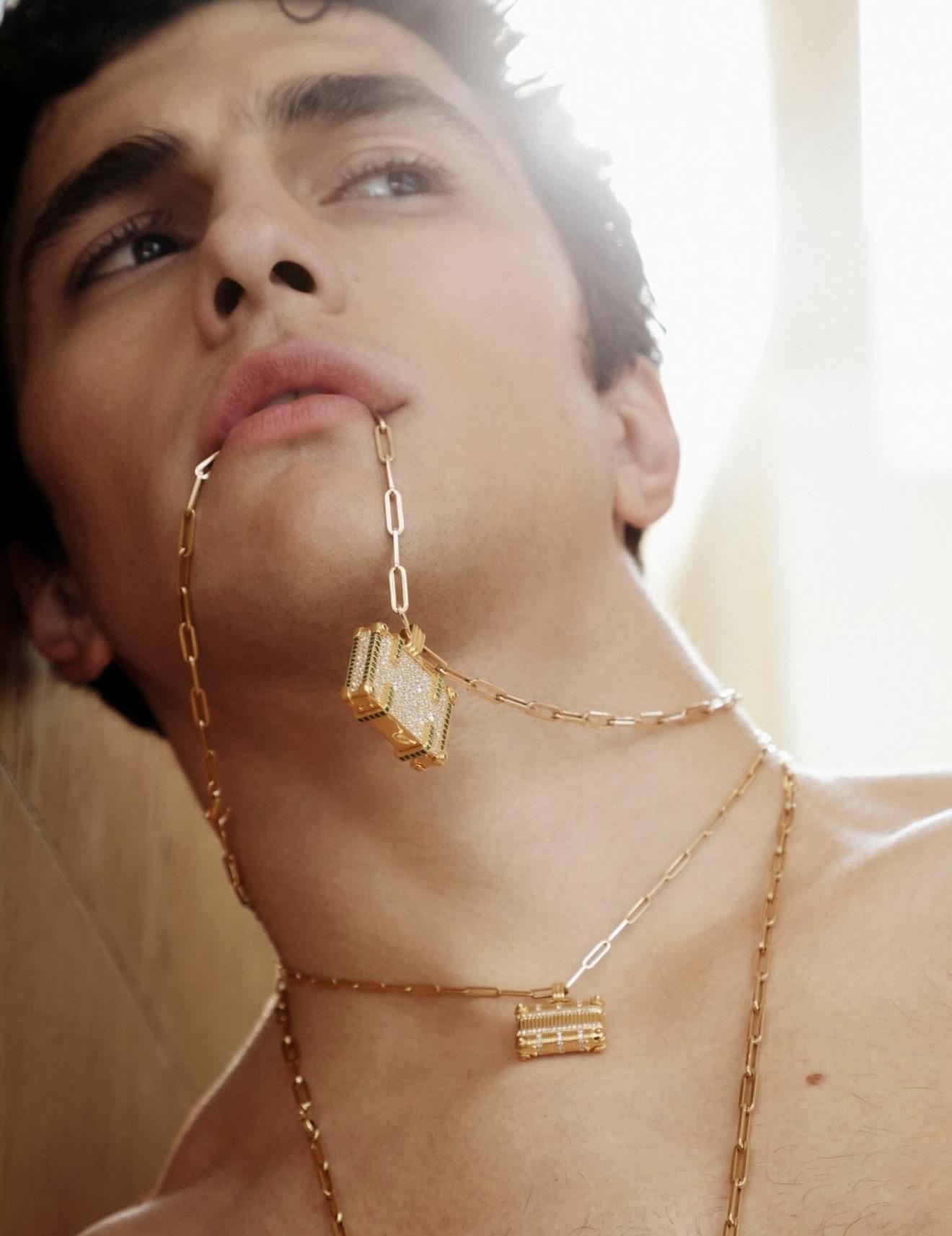 Close-up of a model wearing layered gold chain necklaces with geometric pendants, styled across the neck and face