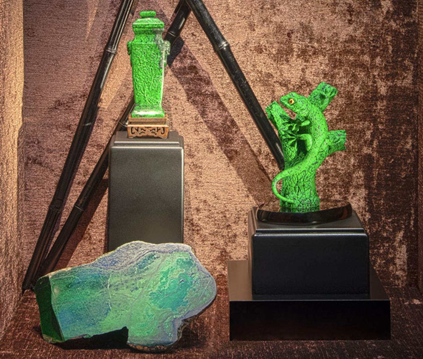 Maw sit-sit gecko carving in vibrant green stone displayed with raw specimen and carved vessel.