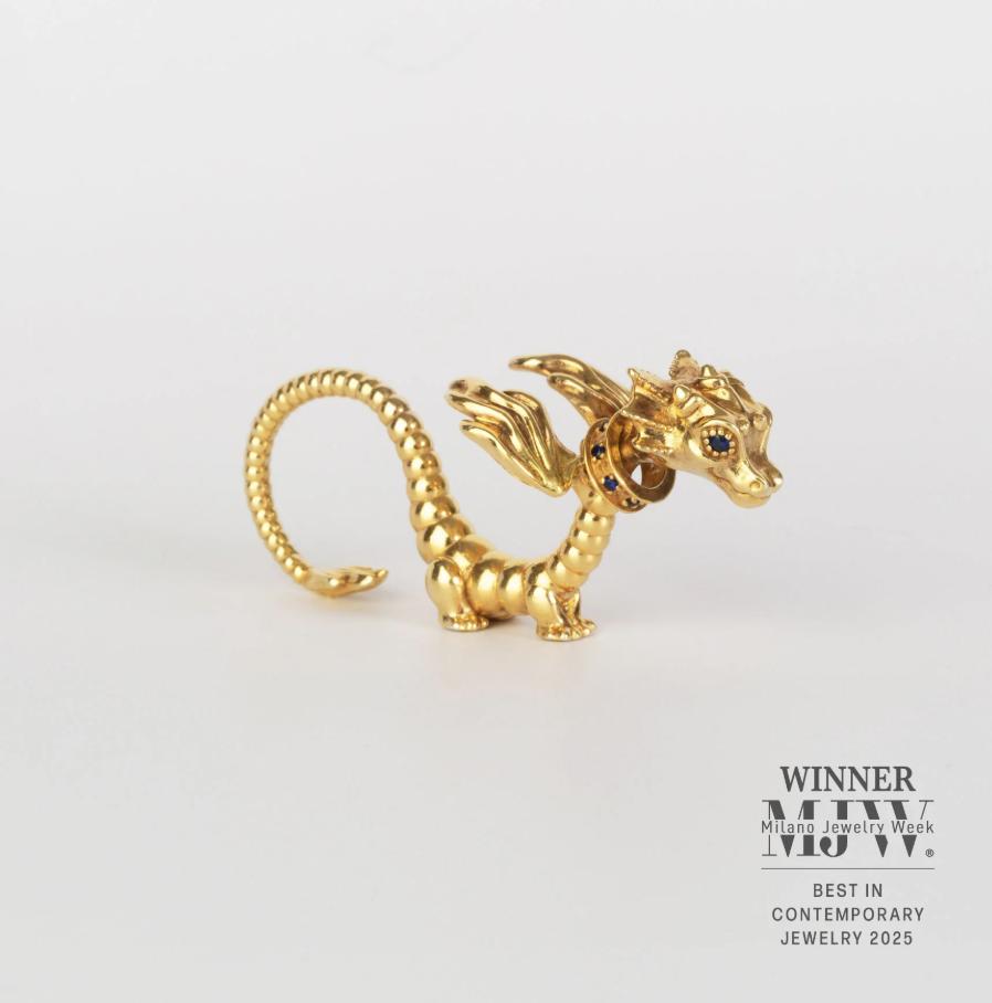 Sculptural gold vermeil dragon ring with outstretched wings, a curled tail and blue sapphire details on a white background.