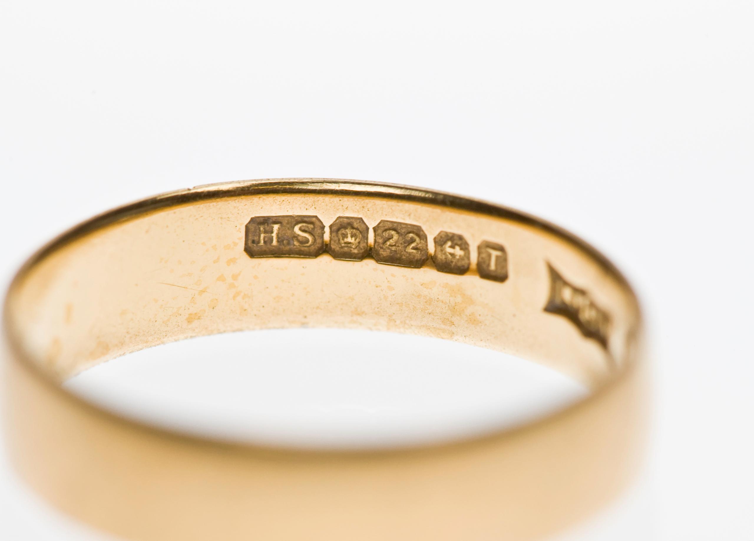Close-up of stamped hallmarks inside a gold ring, including a 22-carat fineness mark